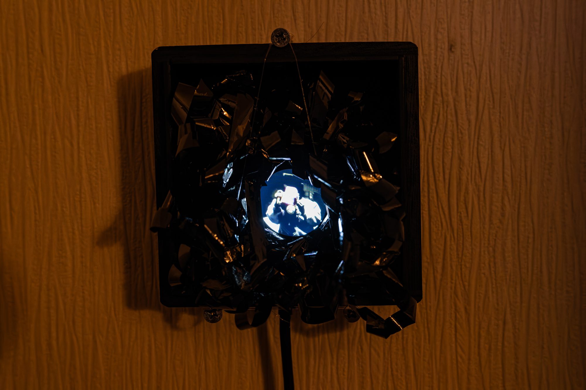 Wooden box on the wall, round LCD glowing among tape